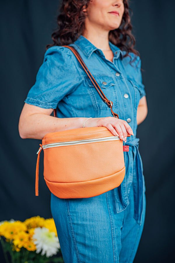 Sac en cuir de couleur pêche. Sac zippé arrondi. porté à l'épaule. Fait à la main