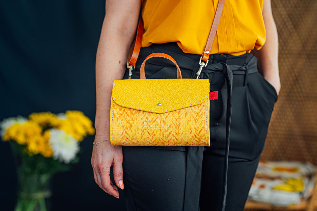 Petite sacoche en cuir jaune portée en bandoulière. Fait à Montréal.